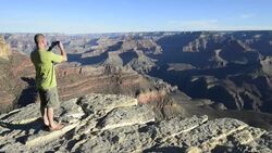 Middle aged man takes a picture of the Grand Canyon Stock Footage