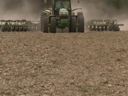 Slow tilt up to tractor moving across the rice field towards the camera. Stock Footage