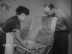 1953: BABY'S EARLY MONTHS: Brunette mother bathing baby boy in bath section of changing table w/ father watching. [SOT Dr. Spock saying caring for baby creates sense of belonging for parents & baby...]... Instructional Video