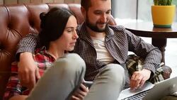 young couple sitting on sofa and using gadgets Stock Footage