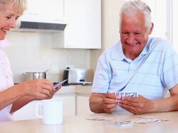 Senior couple sitting at counter playing cards Stock Footage