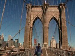 Woman and dog walking away from the camera across the Brooklyn Bridge spanning the East River between Brooklyn and Manhattan  Stock Footage