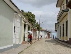 Trinidad Cuba cobblestone streets with people moving and relaxing in their lives Stock Footage