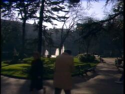 MS Shadows in city park with sunlit fountain, people passing, Paris Stock Footage