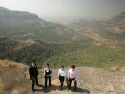 Four business people standing on the cliff of mountain Stock Footage