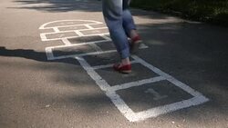 Slow motion shot of a young adult woman playing hopscotch outdoors Stock Footage