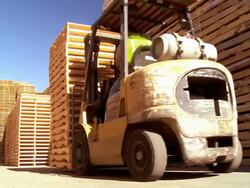 fork lift removes stack of wooden pallets from pallet storage area at pallet repair and manufacturing plant / Fontana, California, USA Stock Footage