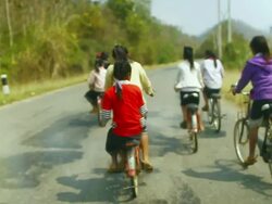 MS SLO MO Shot of group of girls riding bicycles on country road / Road from Luang Prabang to Nong Khio, Luang Prabang, Laos Stock Footage