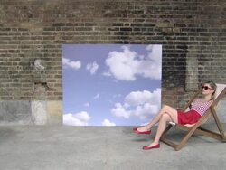 Zoom out from sky backdrop to show girl in deckchair Stock Footage