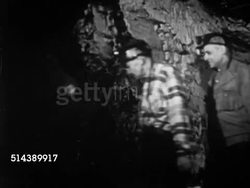 1952: COAL MINING: VS Miniature train moving underground along tracks, carrying miners, mine workers walking through tunnels, coal cutter machinery moving into place, cutting into mine wall of soft coal (the Pittsburgh Coal Seam). Steel industry Instructional Video