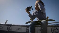 skater sitting on dog bowl looking at his phone venice california skatepark Stock Footage