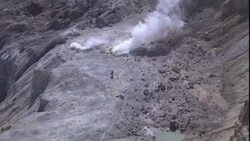 A volcanologist approaches a smoking volcano and crater. Stock Footage