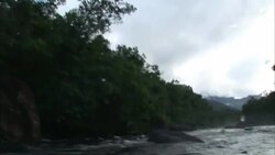 A boat travels down the tree-lined and boulder strewn Kerep River. Stock Footage
