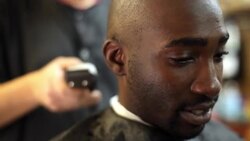 Customer chats and stares ahead while barber trims and shaves his head in local barbershop Stock Footage