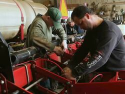 MS Two workers installing wiring for computer system on farm planter / Chelsea Michigan Stock Footage