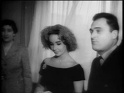 B/W 1950s Elizabeth Taylor in feather hat standing next to Mike Todd at press conference Stock Footage