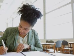African American adult college student studying in brightly lit library Stock Footage