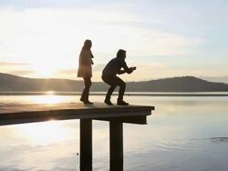 Pan as couple walk along pier, take picture of ducks Stock Footage