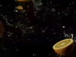 Orange slices falling into water, black background Stock Footage