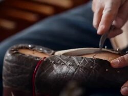 CU PAN boot maker trimming excess leather from sole of cowboy boots Stock Footage