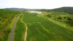 Top view with road on green field, mountain and reservoir. Stock Footage