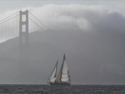 Static frame, sailboat tacks across San Francisco Bay, Golden Gate Bridge north tower in background, fog rolls in Stock Footage