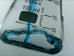 High speed CU blue chemical liquid pouring into glass Stock Footage