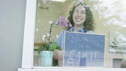 Young business woman opening a small business holding a 'We Are Open' sign Stock Footage