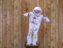 Medium shot boy in astronaut space suit costume posing on pedestal w/wood paneling in background Stock Footage