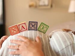 A pregnant women using blocks to spell the word NAME on her stomach. Stock Footage