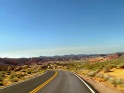 POV driving on two lane desert road through red rocks of Aztec sandstone in Valley of Fire / Overton, Nevada, USA Stock Footage