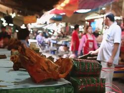  MS SLO MO Boar head on counter at indoor meat market / Vientiane, Laos Stock Footage