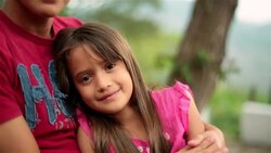 Hispanic teenage brother and younger sister smile at camera Stock Footage