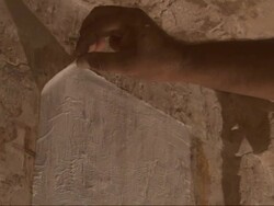 Medium Close Up, static - An archeologist gently peels paper toweling away from a stone wall to reveal Egyptian hieroglyphs Stock Footage