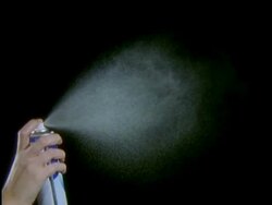 High Speed Aerosol, hand holding can, sprays fine white mist into air against black background Stock Footage