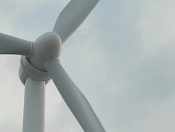 Wind turbine blades and nose cone against mostly cloudy sky - framed left Stock Footage