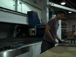 Pan to the right on medium full shot of as man as he sorts cut sheets of metal.  Stock Footage