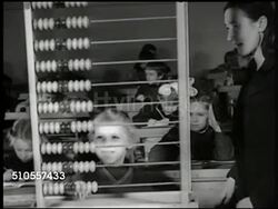 1950: EXT New Russian school, INT Children in classroom (using inkwells) w/ teacher, child using large classroom abacus. DRAMATAZATION: Student enters library, talking w/ woman, hand taking book from shelf, opening book to picture of Vladimir Lenin. Instructional Video
