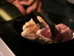 Woman cooks a ham in a cast iron pan Stock Footage