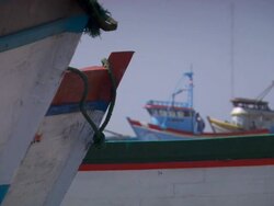 "CU of bow of two colourful wooden boats, more boats in b/g with men milling around, on beach, Trujillo, Peru [PerÃƒÂº]" Stock Footage