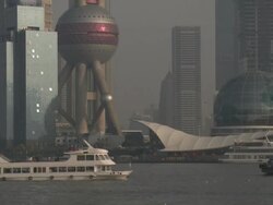 Tilt down Shanghai TV tower as boats sail through the centre of the city, China Stock Footage