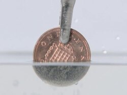 2 pence piece being put into a solution that removes the copper, turning it silver Stock Footage