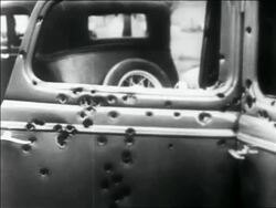 B/W 1934 close up PAN side of car full of bullet holes + with broken windows / Bonnie + Clyde's car Stock Footage