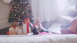 Affectionate couple relaxing in socks with feet up on sofa facing Christmas tree Stock Footage