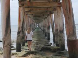 MS View of Girl skipping into sea beneath pier pilings at great ocean road / Point Lonsdale, Victoria, Australia Stock Footage