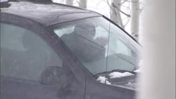 A driver tries to keep warm in his stationary car as snow falls heavily. Stock Footage