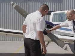 flight instructor and trainee pilot during pre flight inspection of aircraft; instructor demonstrating check of propeller blades, air intakes and exhaust, RED R3D 4K Stock Footage