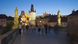 Pedestrians move across the illuminated Charles Bridge at night. Stock Footage