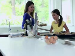 MS DS mother picking up baking sheet of cookies daughter standing watching smiling Stock Footage