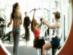 MS young women in gym chatting on weight machines Stock Footage